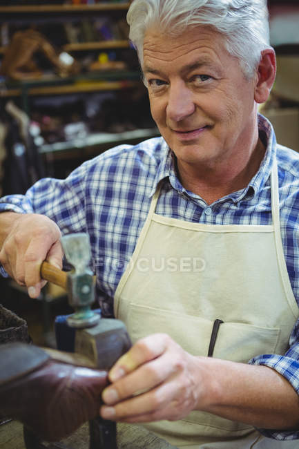 Senior shoemaker hammering on a shoe in workshop — Stock Photo