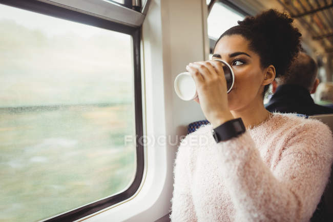 Жінка п'є каву, сидячи в поїзді — стокове фото