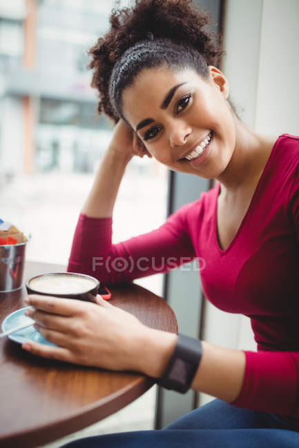Retrato de mujer bonita con café mientras está sentada en el restaurante - foto de stock