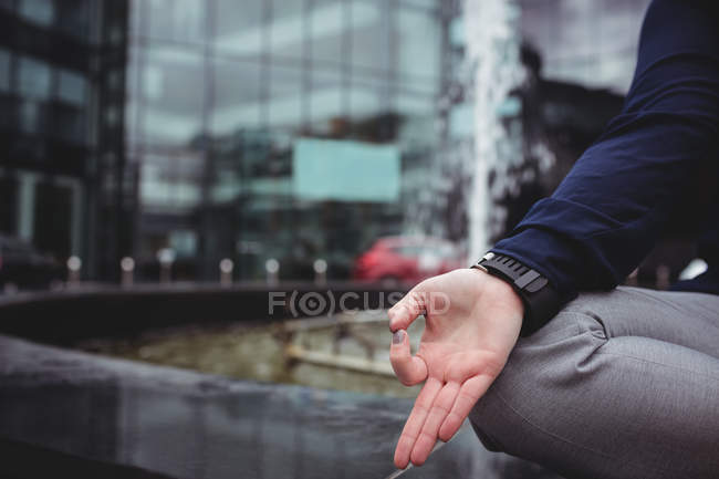 Image recadrée d'une femme faisant du yoga contre un immeuble de bureaux — Photo de stock