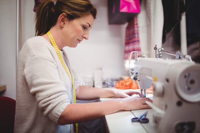 Costureira feminina costura na máquina de costura em estúdio — Fotografia de Stock