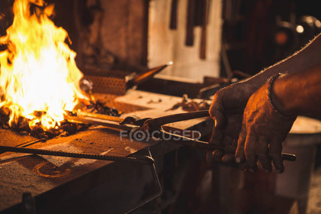 Close-up of blacksmith heating item before forging at work shop — Stock Photo