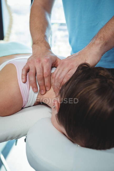 Fisioterapeuta dando fisioterapia al cuello de paciente femenina en clínica - foto de stock