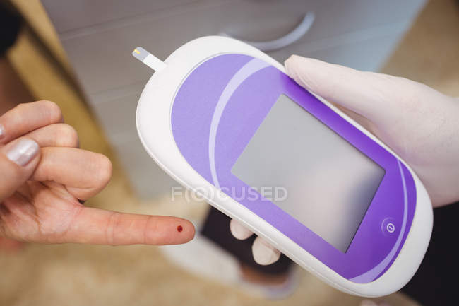 Close-up of doctor measuring sugar level of patient with glucometer at hospital — Stock Photo