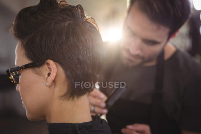 Mujer consiguiendo su pelo recortado en el salón - foto de stock