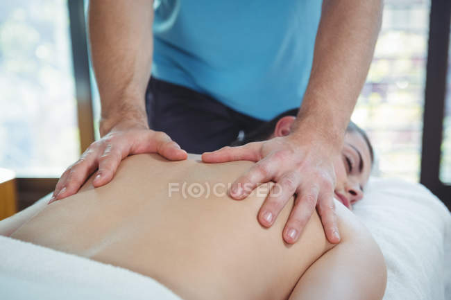 Gros plan du physiothérapeute qui donne de la physiothérapie au dos d'une patiente en clinique — Photo de stock