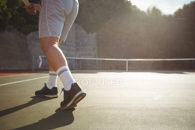 Mann spielt bei weichem Licht Tennis auf dem Platz — Stockfoto