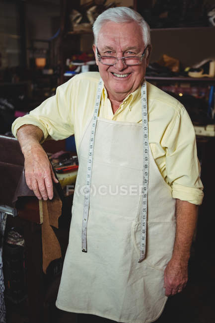 Уверенный улыбающийся сапожник, стоящий в мастерской — стоковое фото