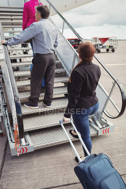 Passageiros subindo nas escadas e entrando no avião no aeroporto — Fotografia de Stock