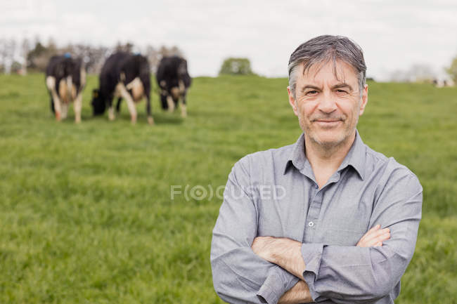 Retrato del veterinario sonriente y confiado de pie en el campo cubierto de hierba - foto de stock