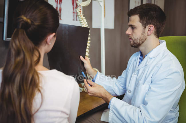 Чоловічий терапевт, який показує рентгенівський знімок пацієнтки у клініці — стокове фото