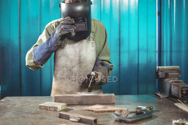 Female welder holding welding arch in workshop — Stock Photo