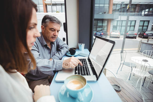 Hombre y mujer usando laptop en cafetería - foto de stock