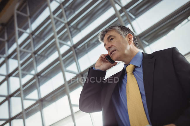 Businessman talking on mobile phone in waiting area at airport terminal — Stock Photo