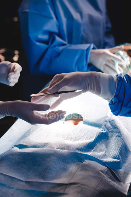 Chirurghi che danno la lama dell'operazione al collega in sala operatoria dell'ospedale — Foto stock