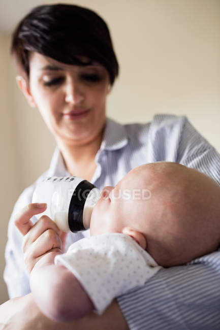 Primo piano della madre che allatta il bambino con il biberon a casa — Foto stock