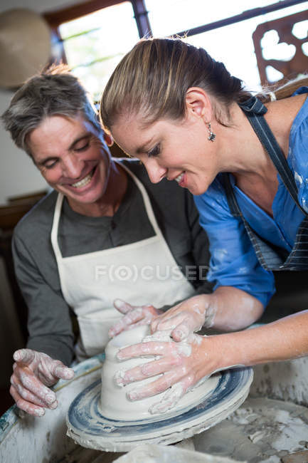 Мужчина-гончар помогает горшечнице в мастерской по гончарному делу — стоковое фото
