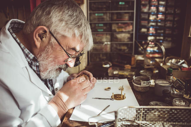 Горолог ремонтирует часы в мастерской — стоковое фото