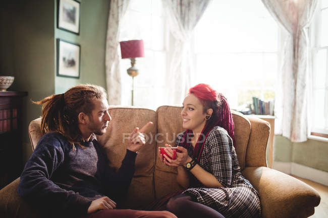 Young hipster couple talking on sofa at home — Stock Photo