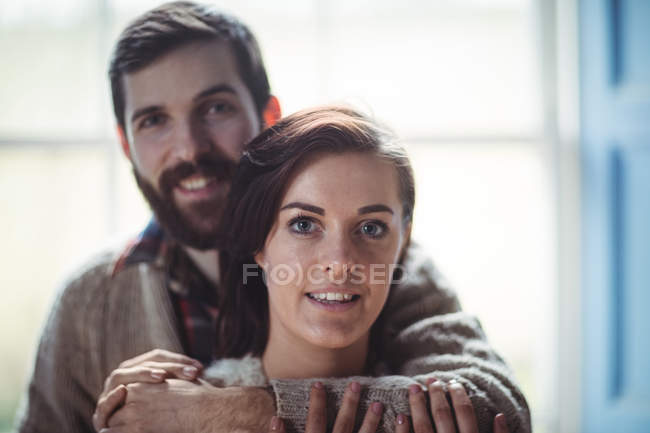 Мужчина обнимает женщину дома и смотрит в камеру — стоковое фото