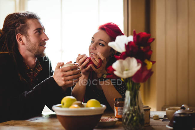 Pareja tomando té mientras está sentada en la mesa en casa - foto de stock