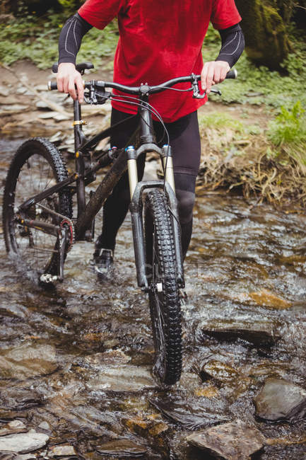 Bassa sezione di ciclista a piedi con bicicletta in torrente al bosco — Foto stock