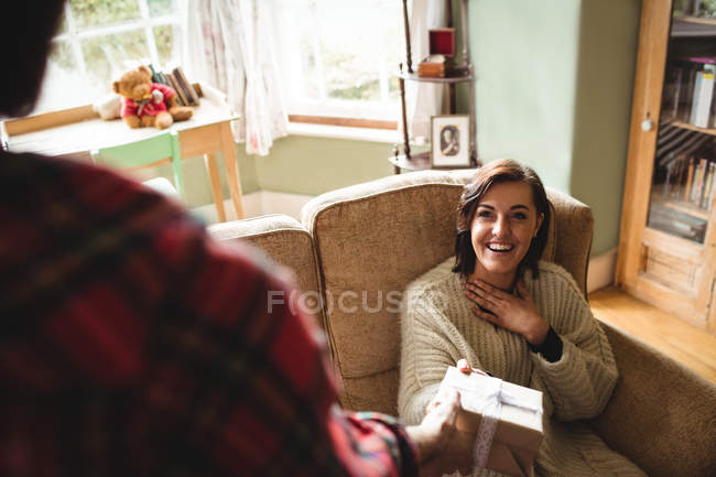 Homem mulher surpreendente com presente na sala de estar em casa — Fotografia de Stock