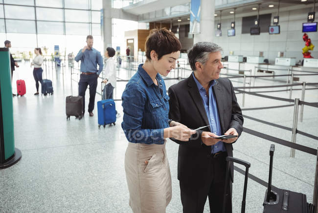 Business man and woman checking their passport in airport terminal — Stock Photo