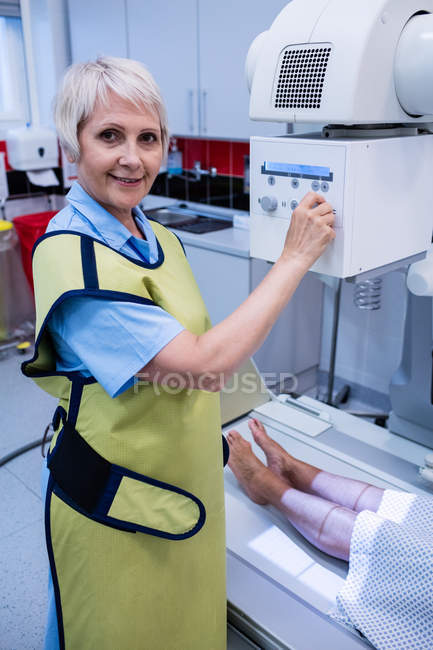 Médico femenino usando máquina de rayos X para examinar al paciente en el hospital - foto de stock