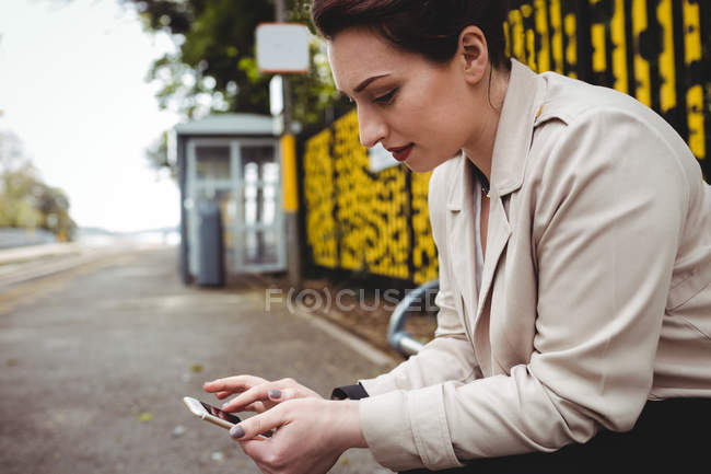 Молодая женщина использует мобильный телефон на вокзале — стоковое фото