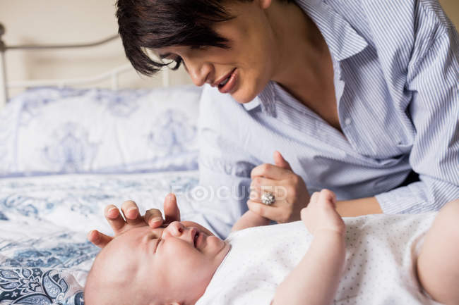 Мама успокаивает плачущего ребенка на кровати дома — стоковое фото