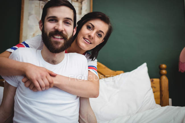 Frau umarmt Mann auf Bett im Schlafzimmer — Stockfoto