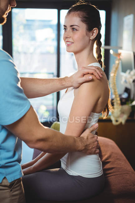 Fisioterapeuta massageando as costas da paciente feminina na clínica — Fotografia de Stock