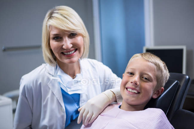 Portrait of smiling dentist and young patient at dentist clinic — Stock Photo