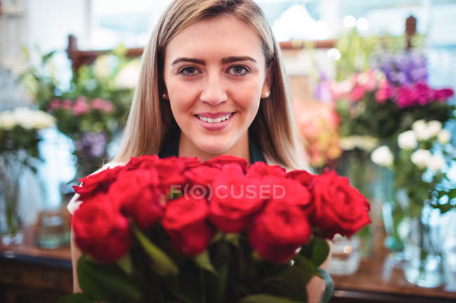 Florista feminina segurando um monte de flores de rosa na loja de flores — Fotografia de Stock