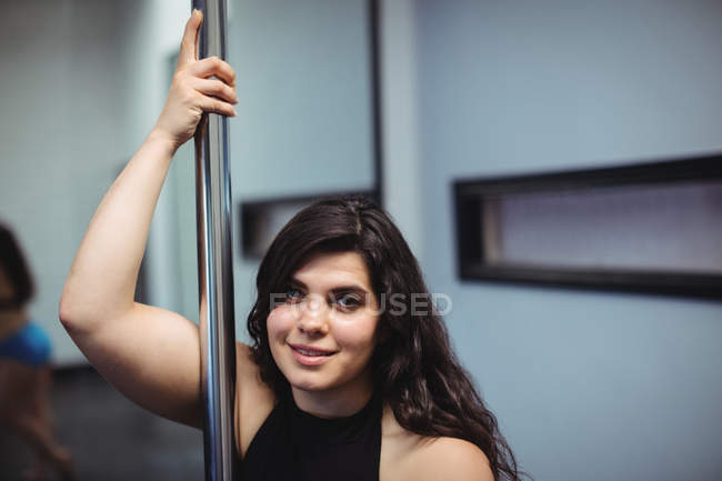 Портрет полюсної танцівниці, що тримає полюс у фітнес-студії — стокове фото