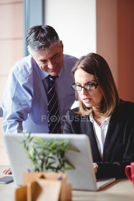 Uomo d'affari discutendo con la donna d'affari sul computer portatile in ufficio — Foto stock