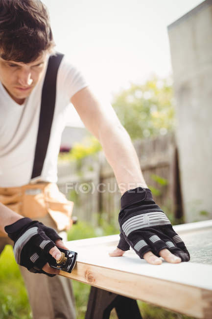 Carpenter leveling wooden frame with block plane outside house — Stock Photo