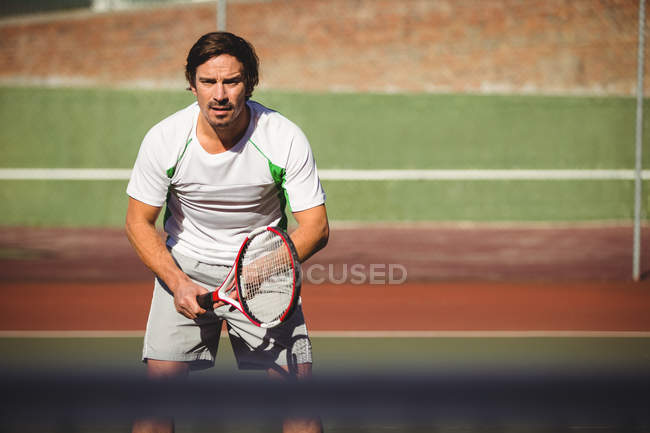 Чоловік грає в теніс у спортивному корт на сонячному світлі — стокове фото