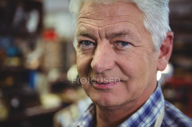 Confiado sonriendo hombre mayor de pie en el taller - foto de stock