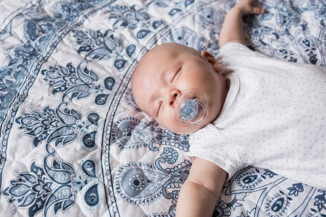 Bebê dormindo com manequim na boca na cama em casa — Fotografia de Stock