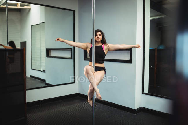 Красивая танцовщица, практикующая танец на шесте в фитнес-студии — стоковое фото