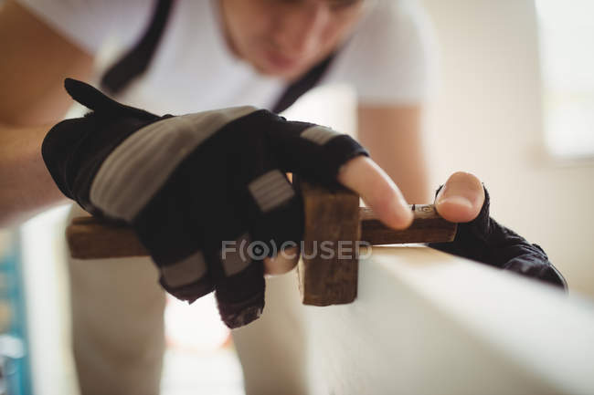 Imagem cortada de Carpenter usando medidor de marcação na porta de madeira em casa — Fotografia de Stock