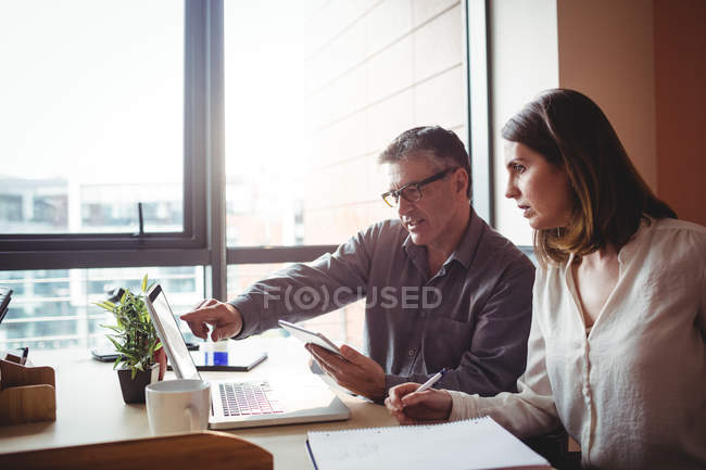 Homem discutindo com colega sobre laptop no escritório — Fotografia de Stock