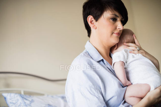 Mãe segurando bebê enquanto ele dorme no quarto em casa — Fotografia de Stock