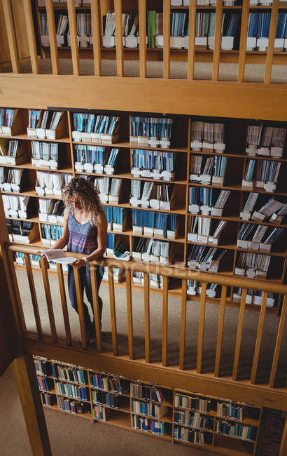 Жінка читає книгу в бібліотеці — стокове фото