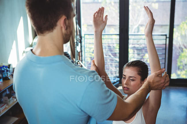 Fisioterapeuta esticando os braços de paciente do sexo feminino na clínica — Fotografia de Stock