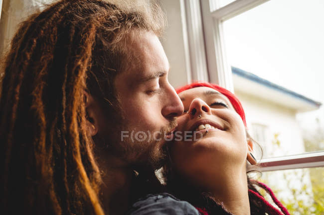 Giovane coppia hipster che abbraccia dalla finestra a casa — Foto stock