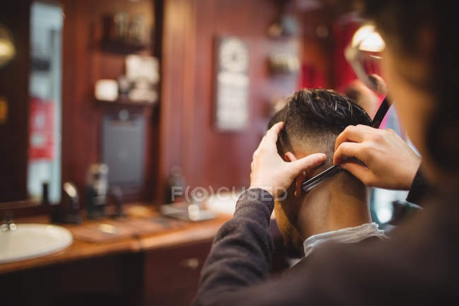 Homme se faire couper les cheveux avec un rasoir dans le salon de coiffure — Photo de stock