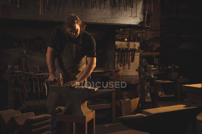 Schmied steht und arbeitet in der Werkstatt — Stockfoto